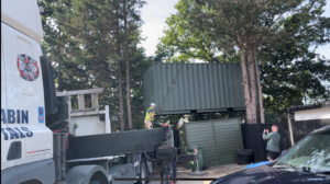 20ft shipping container being offloaded in a tight area with limited access.